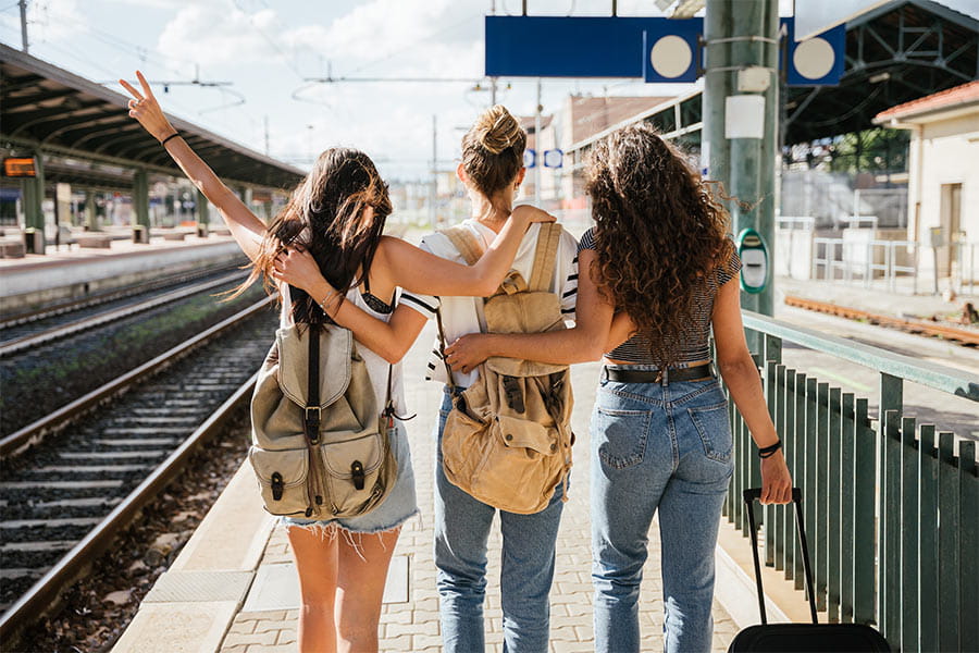 group of three friends walking in a train station