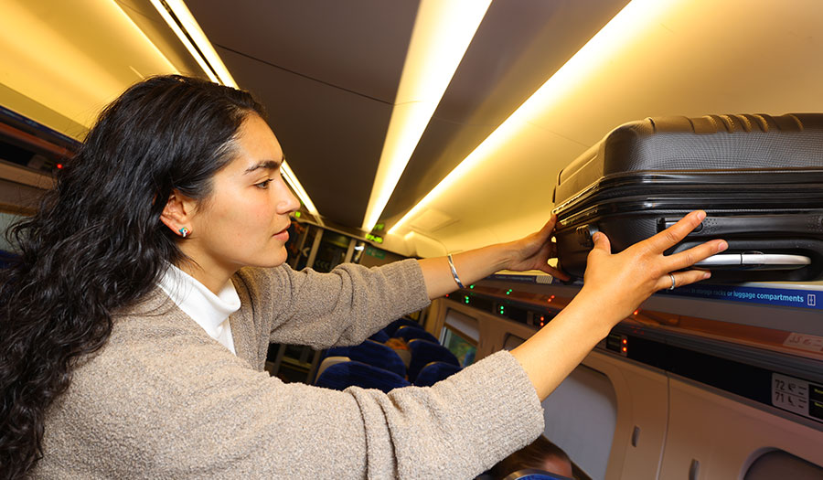 Passenger storing a suitcase in the overhead compartment