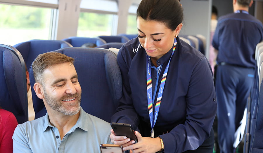 passenger speaking showing his ticket to a member of staff