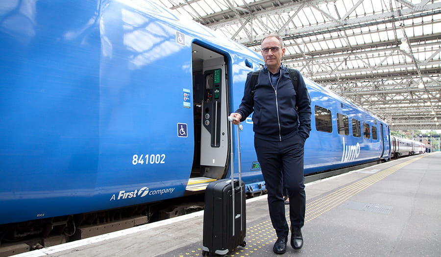 male passenger walking along the platform carrying a small suitcase