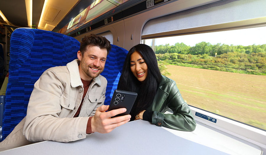 Two passengers looking at their phone smiling