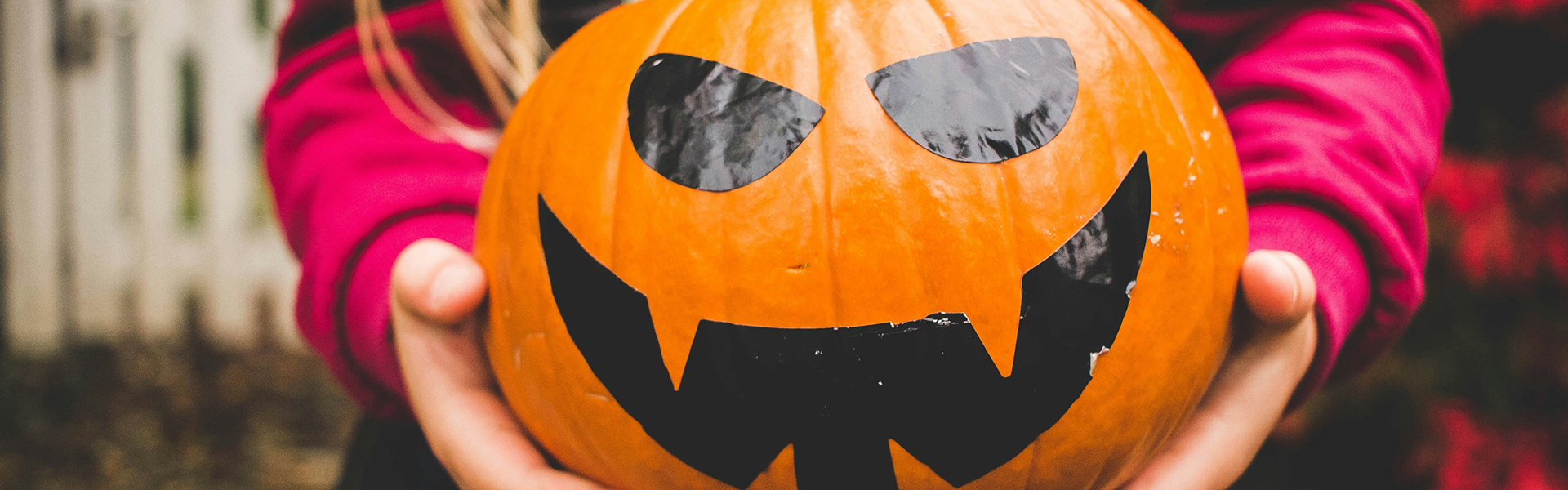 child holding a Halloween jack o' lantern
