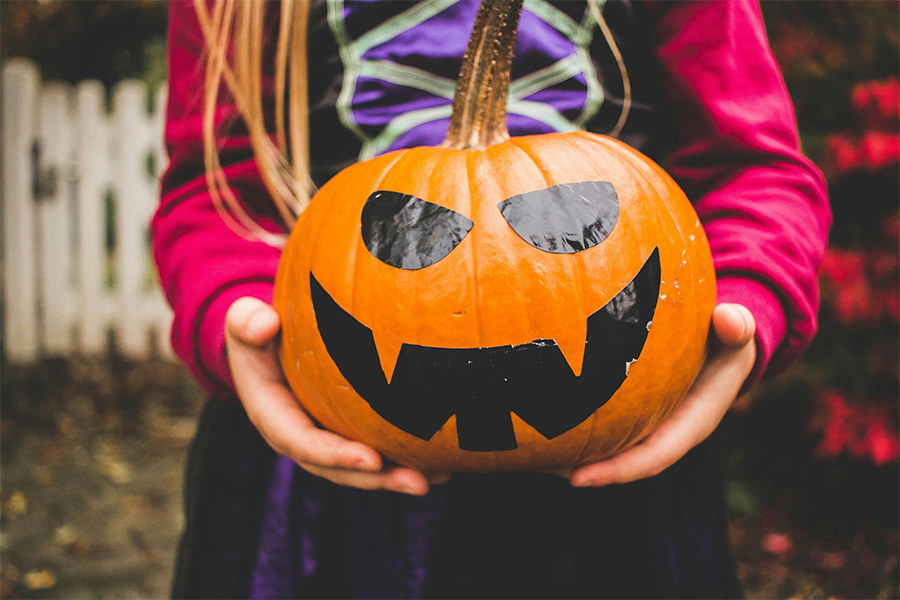 child holding a Halloween jack o' lantern