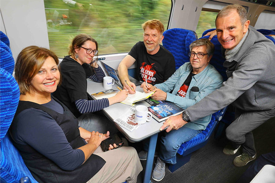 Authors Natalie Jayne Clark, Gordon Brown and Douglas Skelton signing books onboard a Lumo train