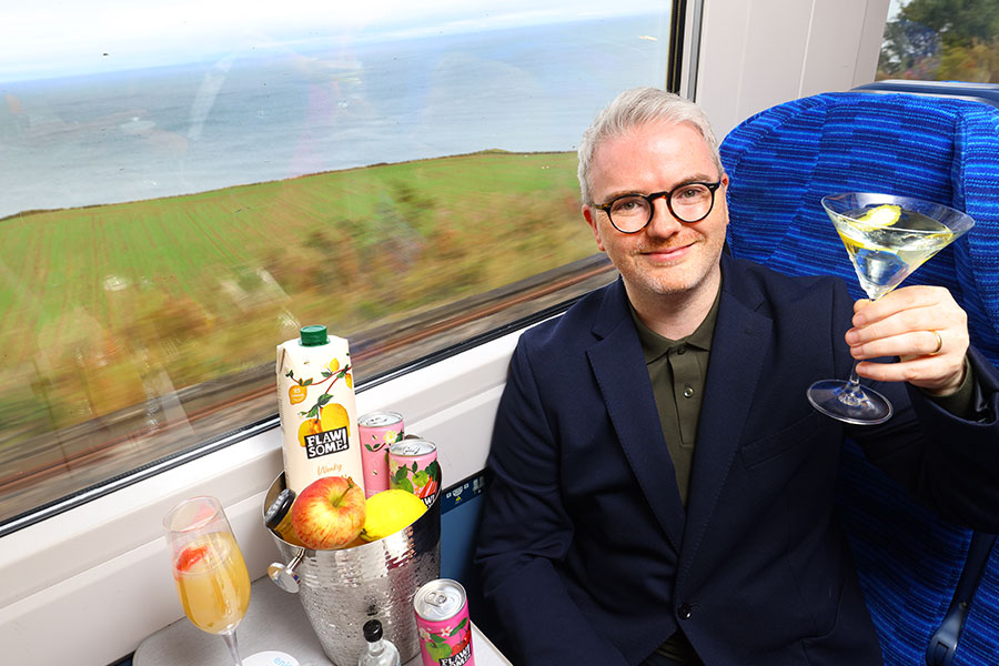 Man holding a glass on a Lumo train