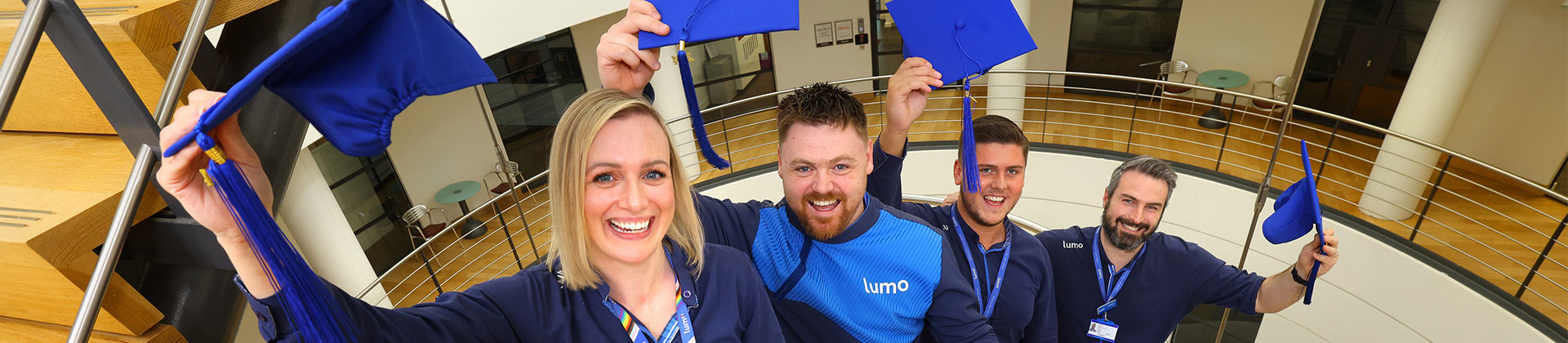 Image of Lumo staff members holding graduation caps
