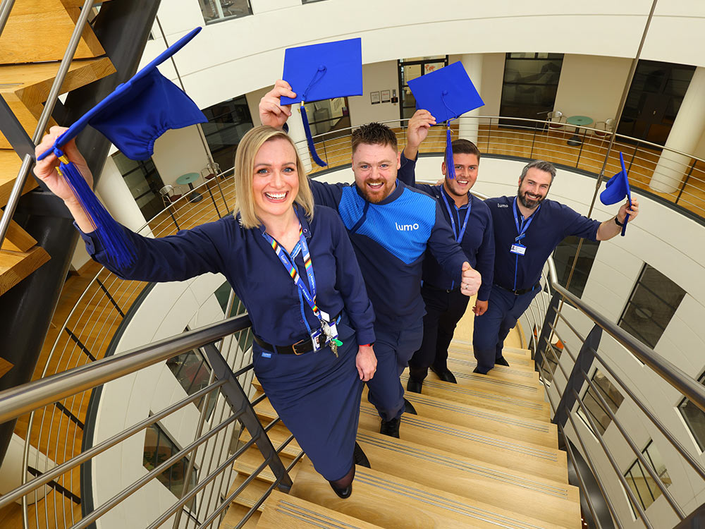 Image of Lumo staff members holding graduation caps