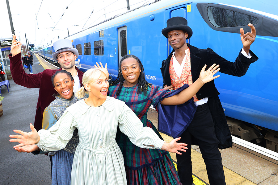 (L-R) Alicia McKenzie, Benjamin Storey, Emily Ash, Gigi Noel-King and Taku Mutero standing in front of a Lumo train