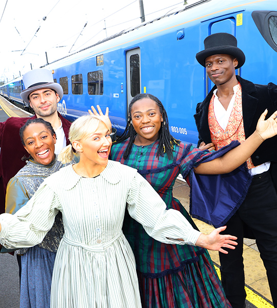 (L-R) Alicia McKenzie, Benjamin Storey, Emily Ash, Gigi Noel-King and Taku Mutero standing in front of a Lumo train