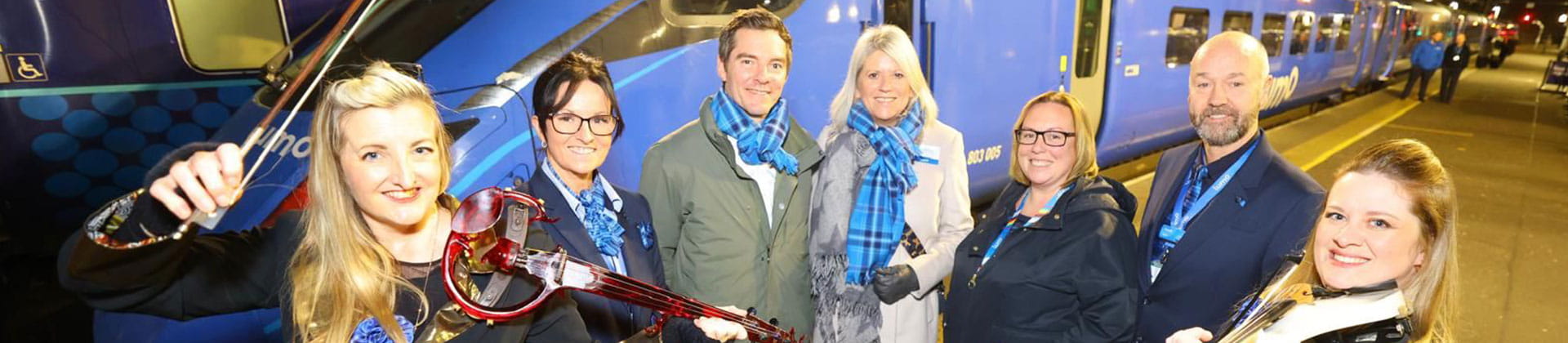 Lumo representatives next to two violinists at Glasgow station
