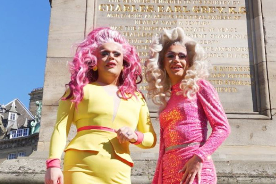 two drag queens standing in front of Grey's Monument in Newcastle
