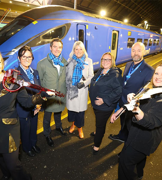 Lumo representatives next to two violinists at Glasgow station
